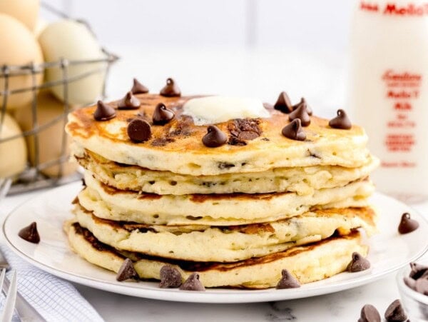 A stack of chocolate chip pancakes topped wither butter