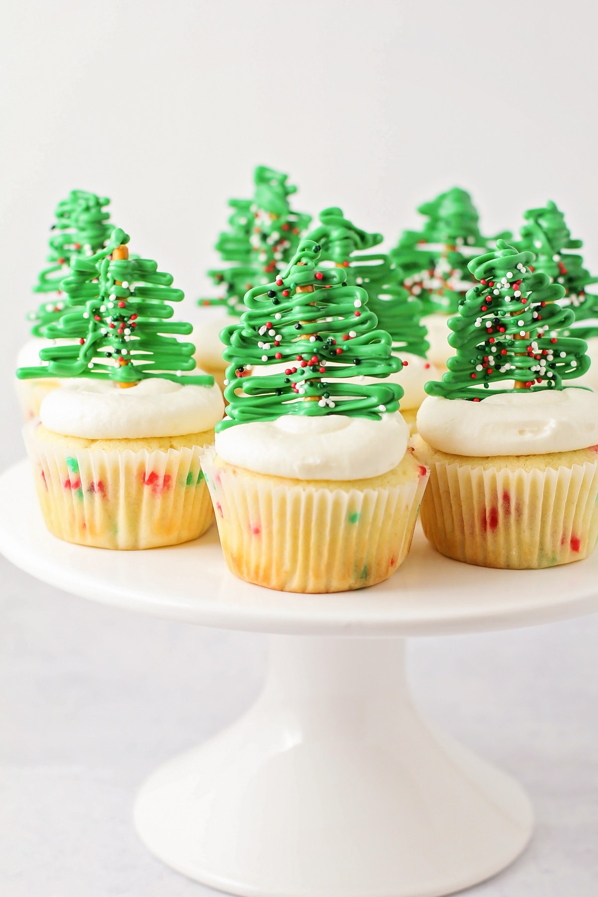 Close up of Christmas cupcakes on a white cake platter.