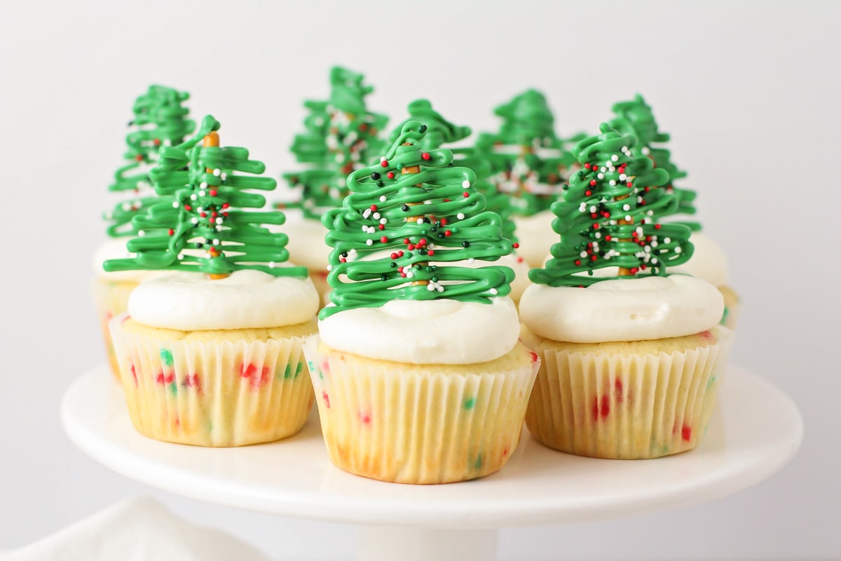 Close up of Christmas cupcakes on a white cake platter.