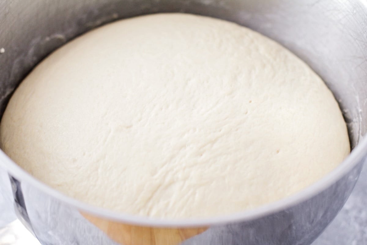 White bread dough rising in a bowl.