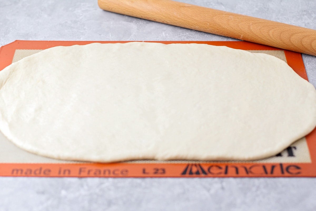 Rolling white bread dough on a slipmat.