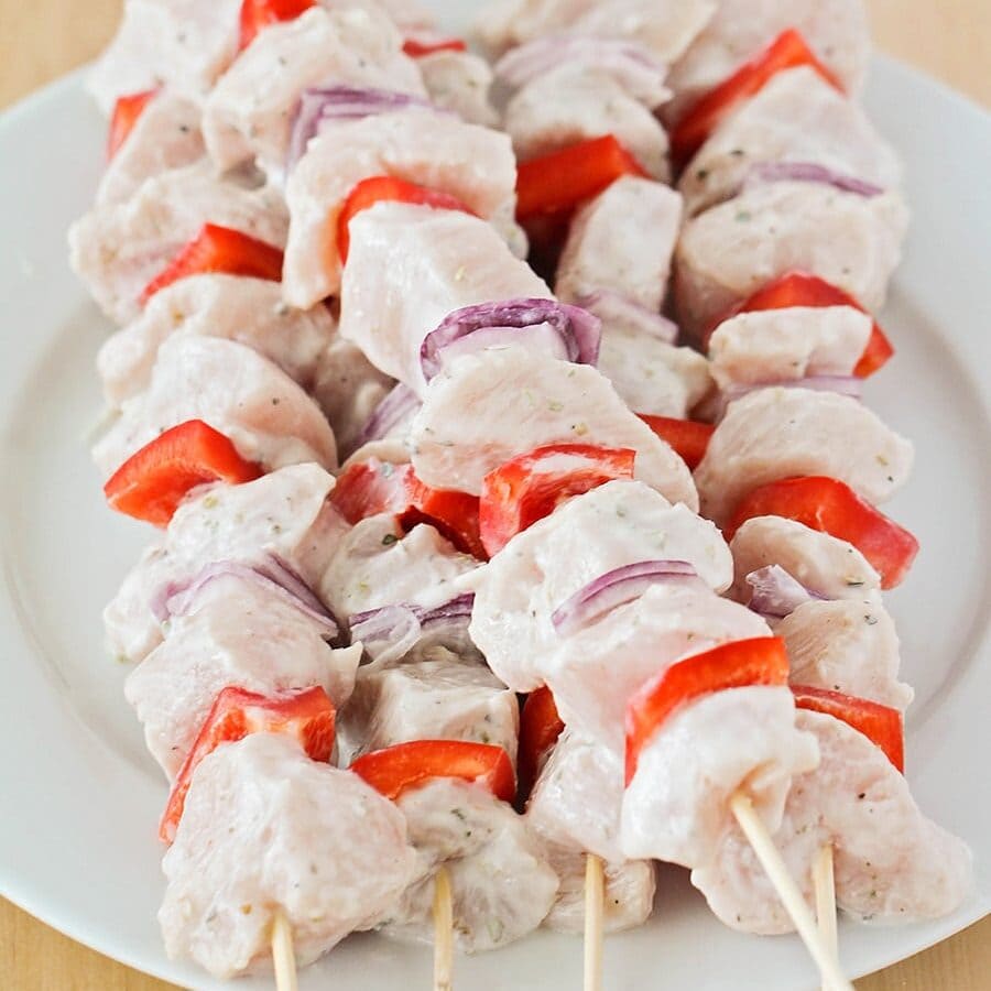 Greek chicken souvlaki skewers marinating before going in the oven.
