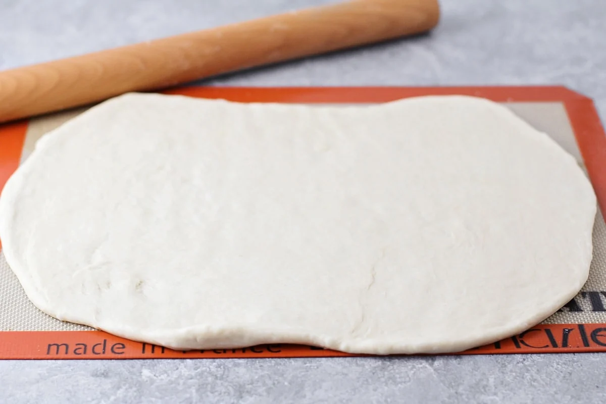 Soft, simple, and no-fail, this homemade French bread has simple step-by-step directions and comes out perfect every time! Rolling one dough ball out into a rectangle.