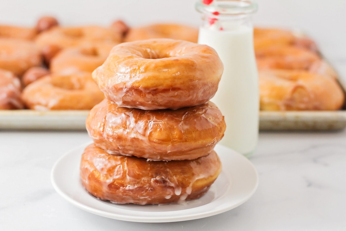 A stack of three homemade donuts on a white plate. 
