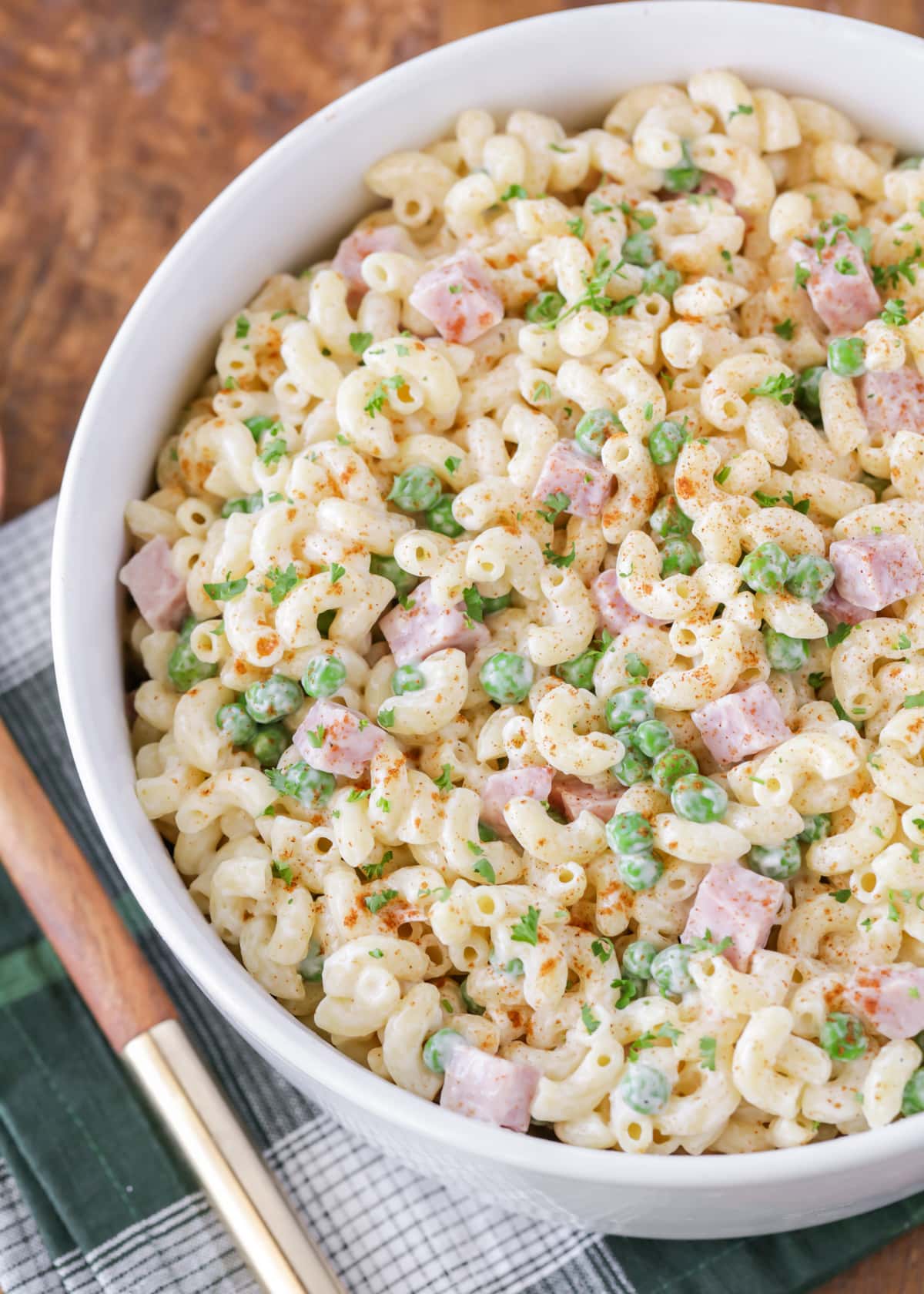 White bowl filled with macaroni salad and garnished with fresh herbs.