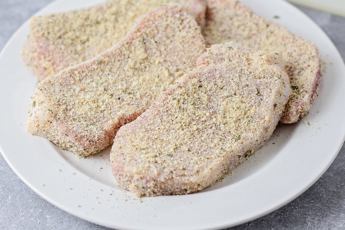 Pork chops with a parmesan crust on a white plate.