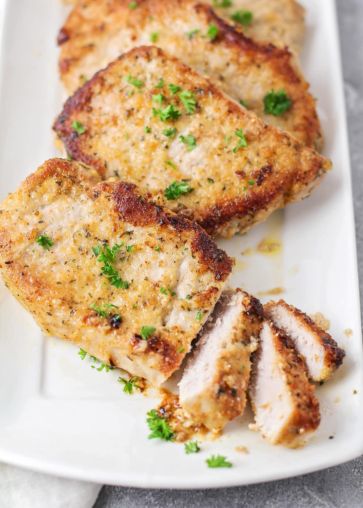 Sliced best pork chops recipe on a white platter.