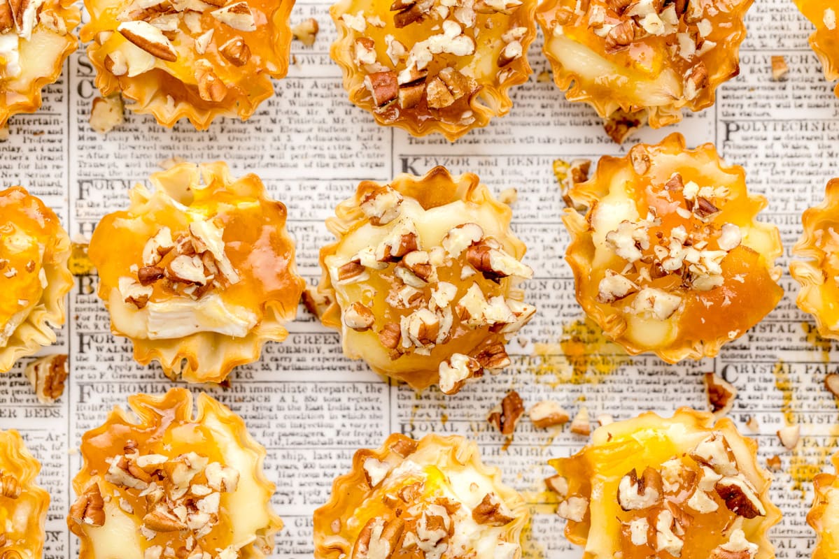 Close up of several brie phyllo tarts topped with crushed nuts.