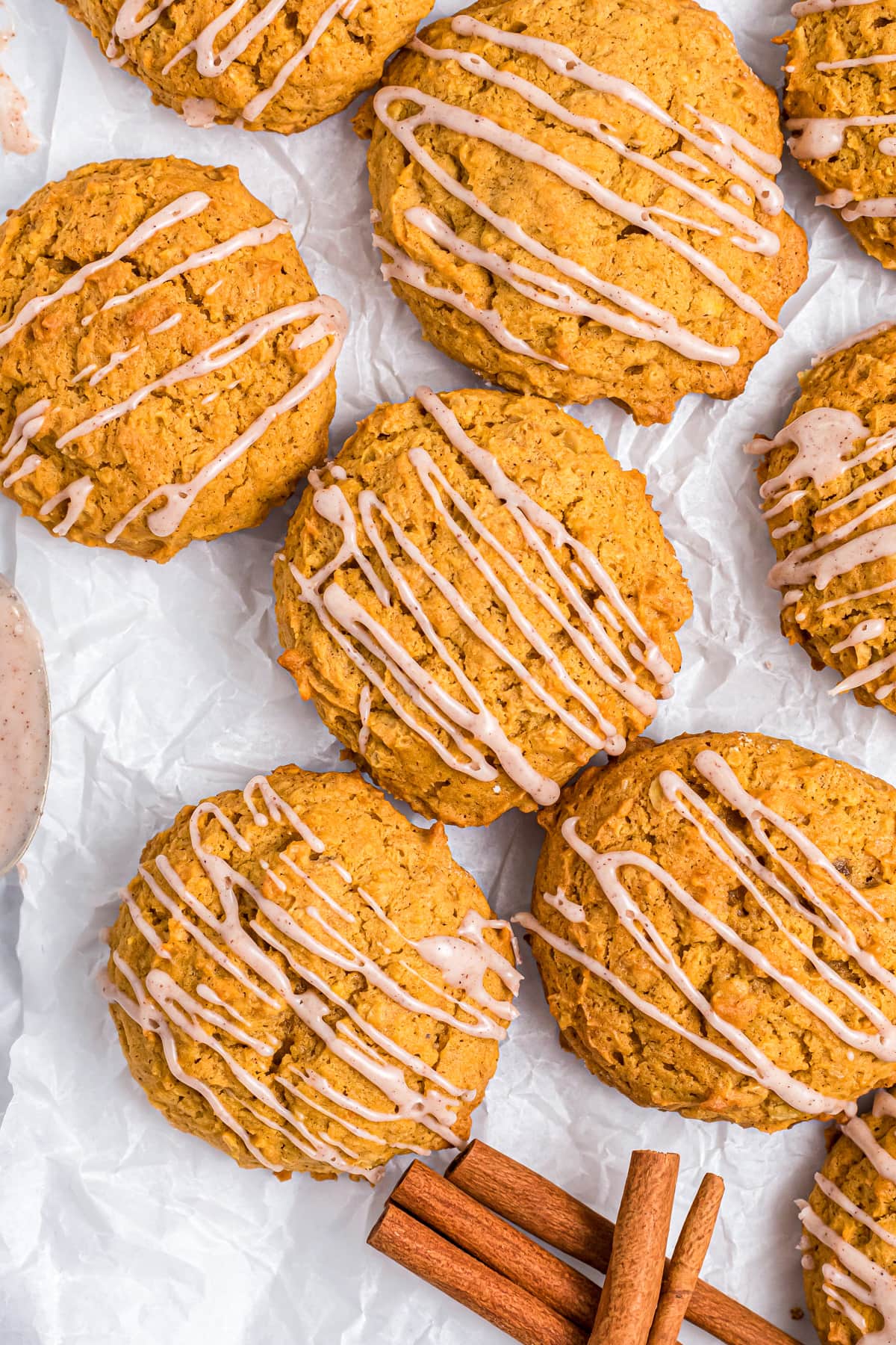5 Pumpkin oatmeal cookies drizzled with glaze on a sheet of wax paper.