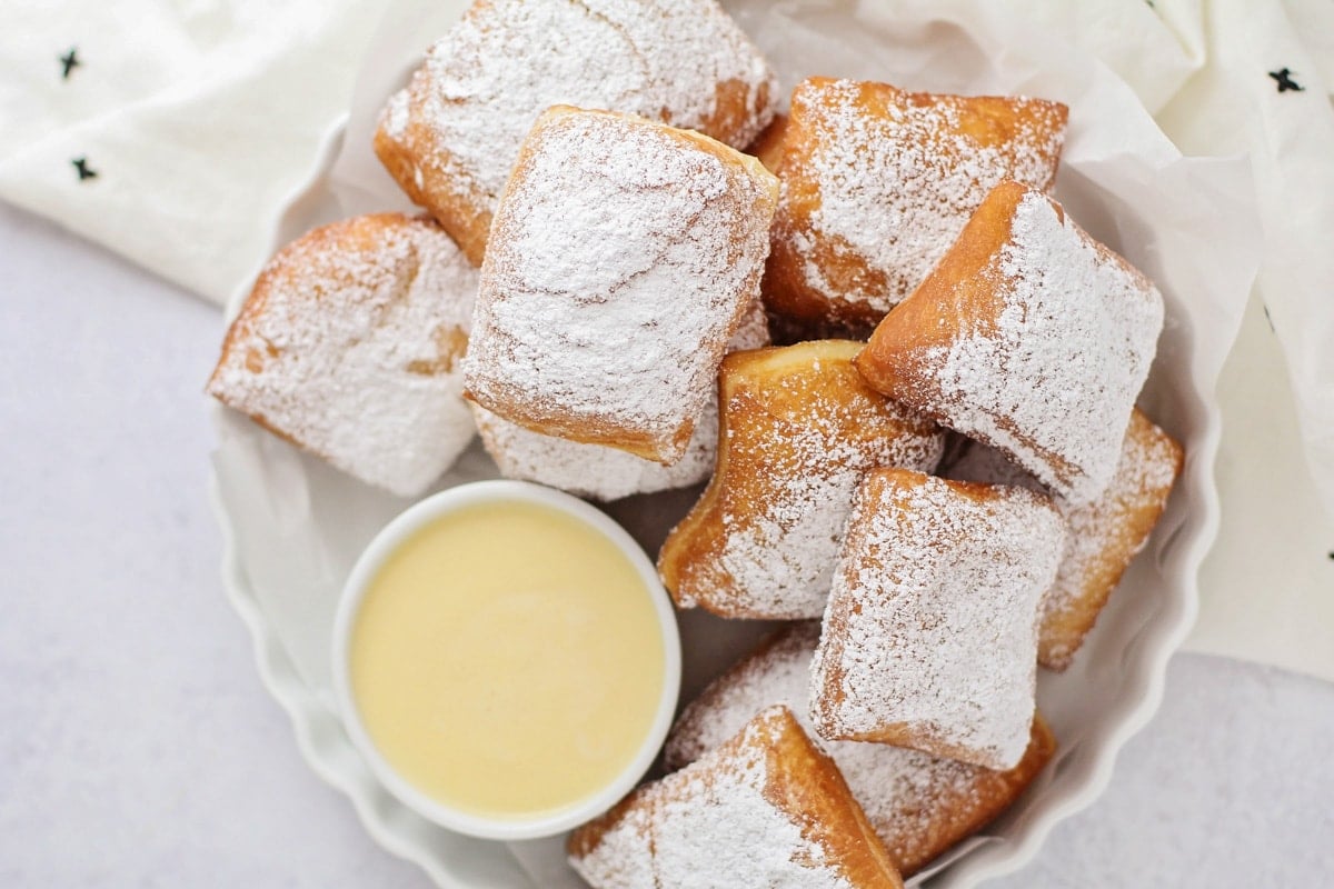 Homemade Beignets recipe stacked in dish with Angalise sauce.