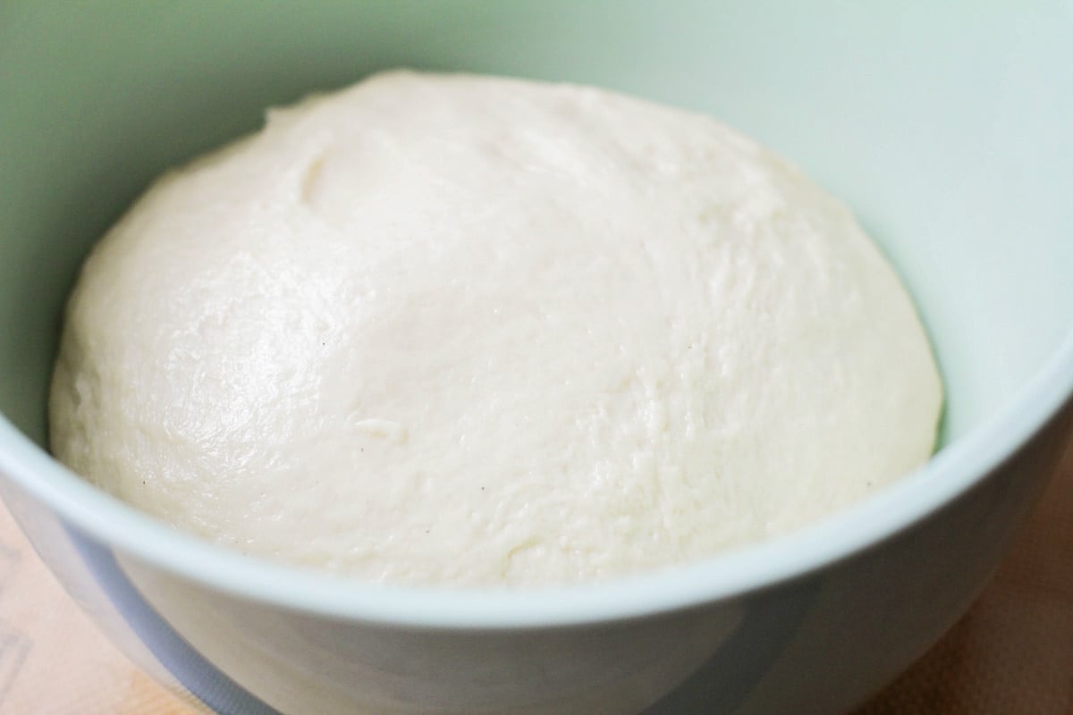 Risen beignet dough placed in a bowl.