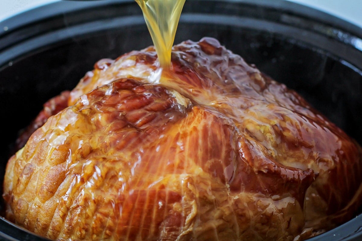Pouring juices over crockpot brown sugar ham.