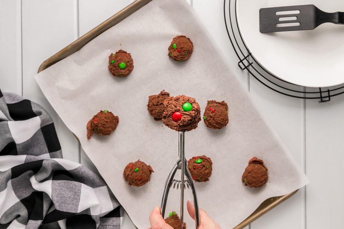 Ball of chocolate christmas cookies scooped on a baking sheet.
