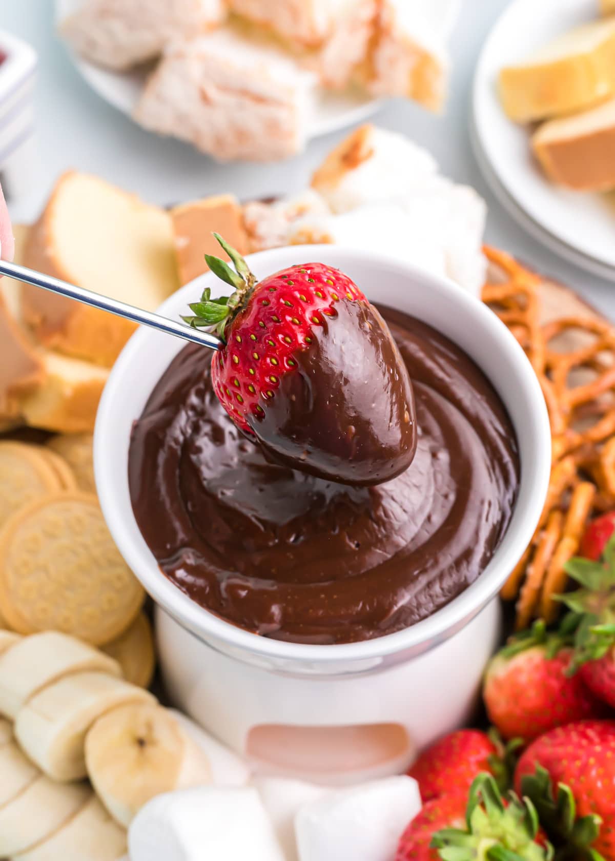 Dipping a fresh strawberry in a pot of chocolate fondue.