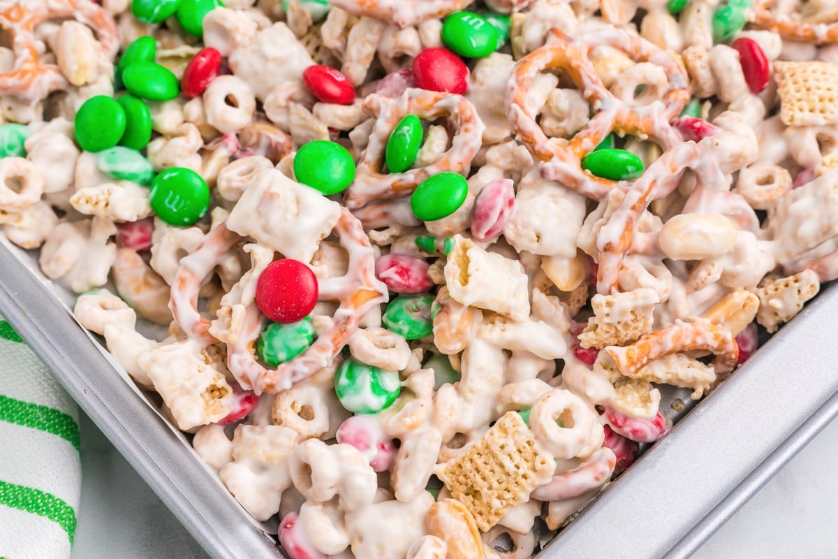Close up of Christmas chex mix spread on a baking sheet to cool.