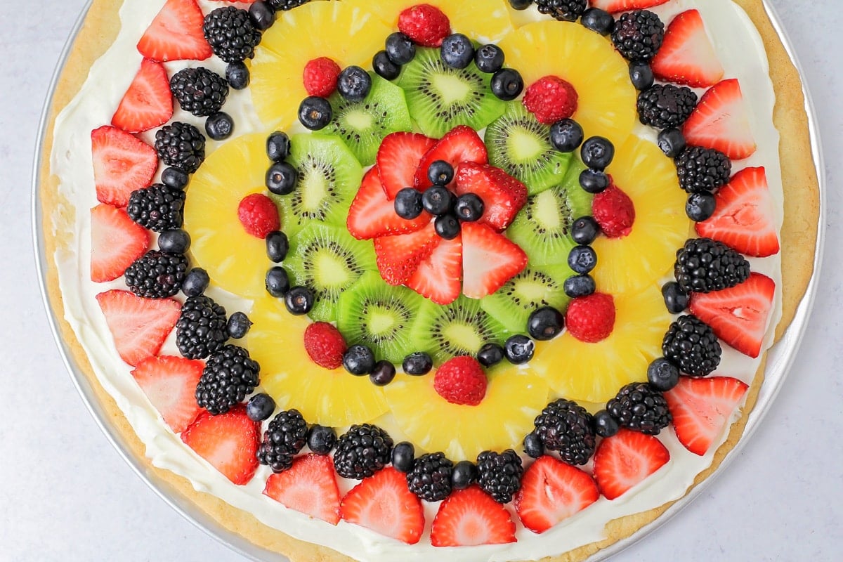 Easy fruit pizza recipe topped with fresh fruit and cream cheese frosting.