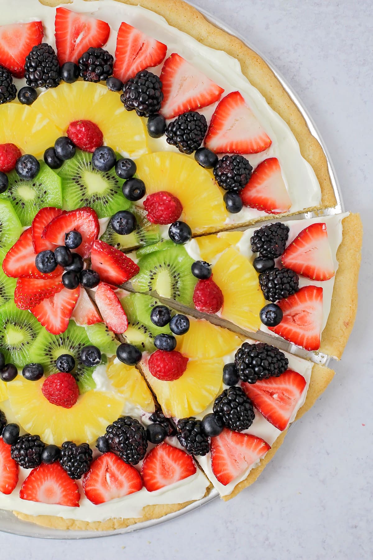 Sliced fruit pizza recipe with sugar cookie crust and fresh fruit.