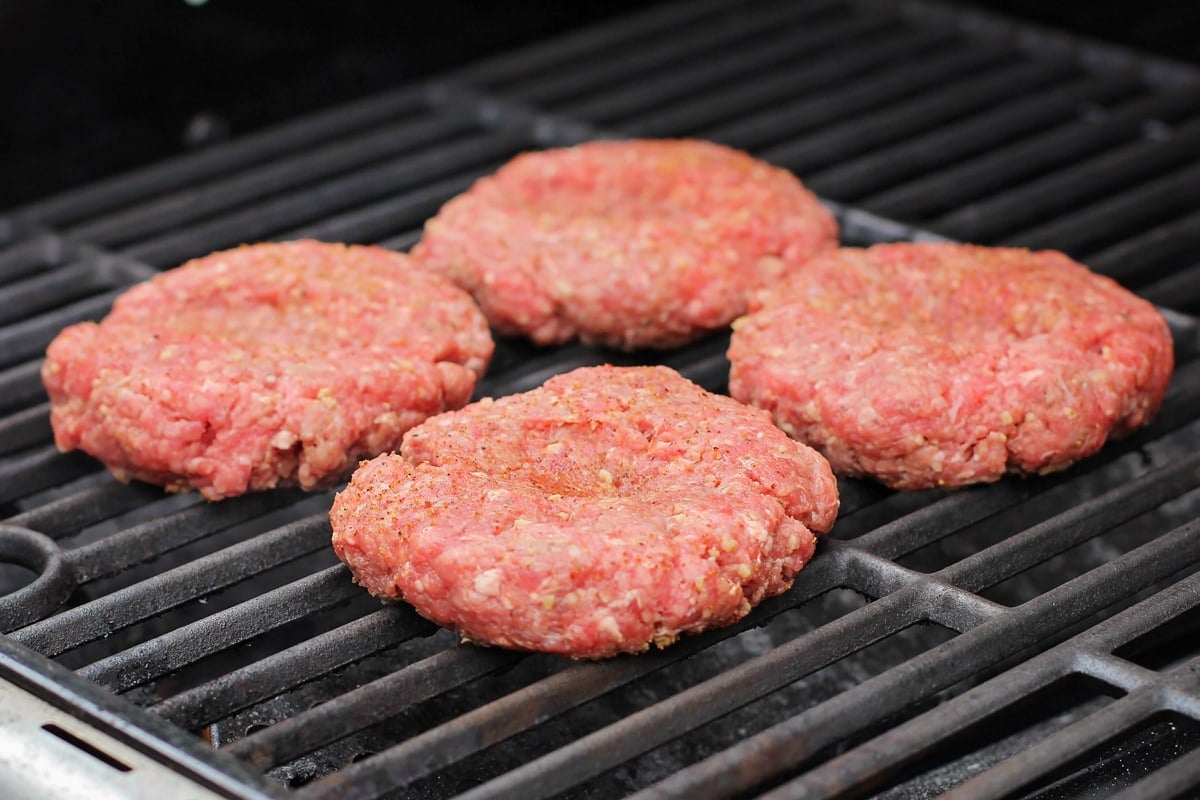 4 hamburger recipe patties cooking on a grill.
