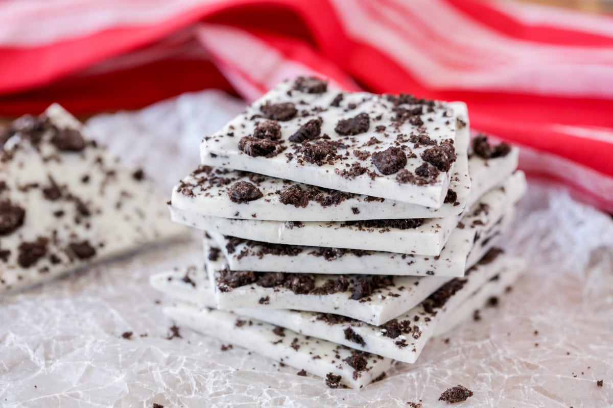 Oreo cookie bark squares stacked on wax paper.