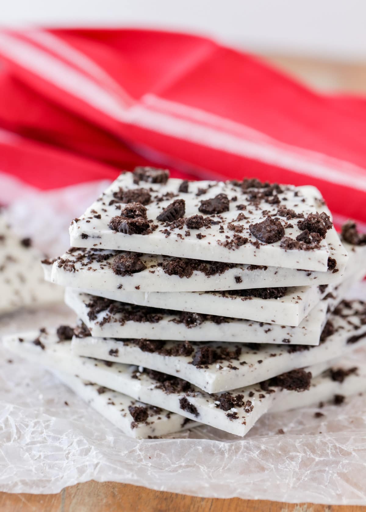 Pieces of oreo cookie bark stacked in a tower on wax paper.