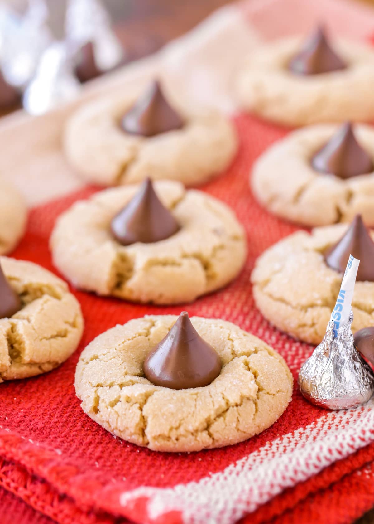 Peanut butter hershey kiss cookies on a red dish towel.
