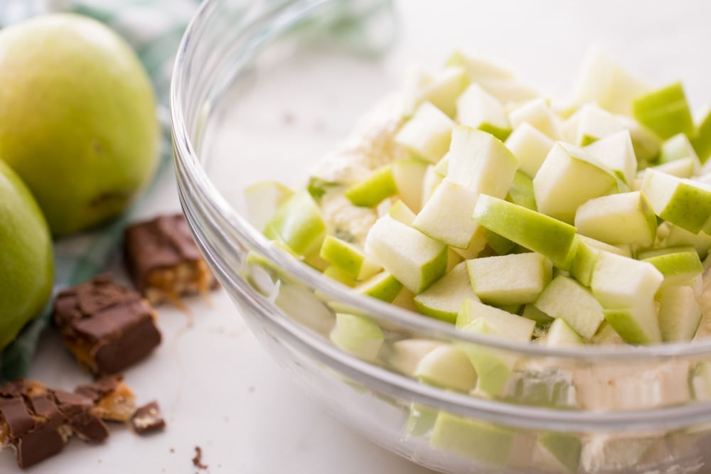 Chopped ingredients poured into a bowl for snicker apple salad.