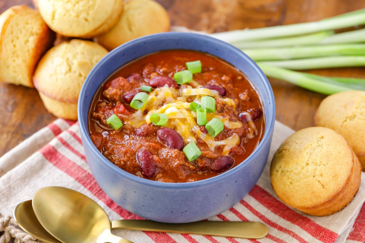 Best Chili Recipe served in a red bowl with cheese and fresh lime.