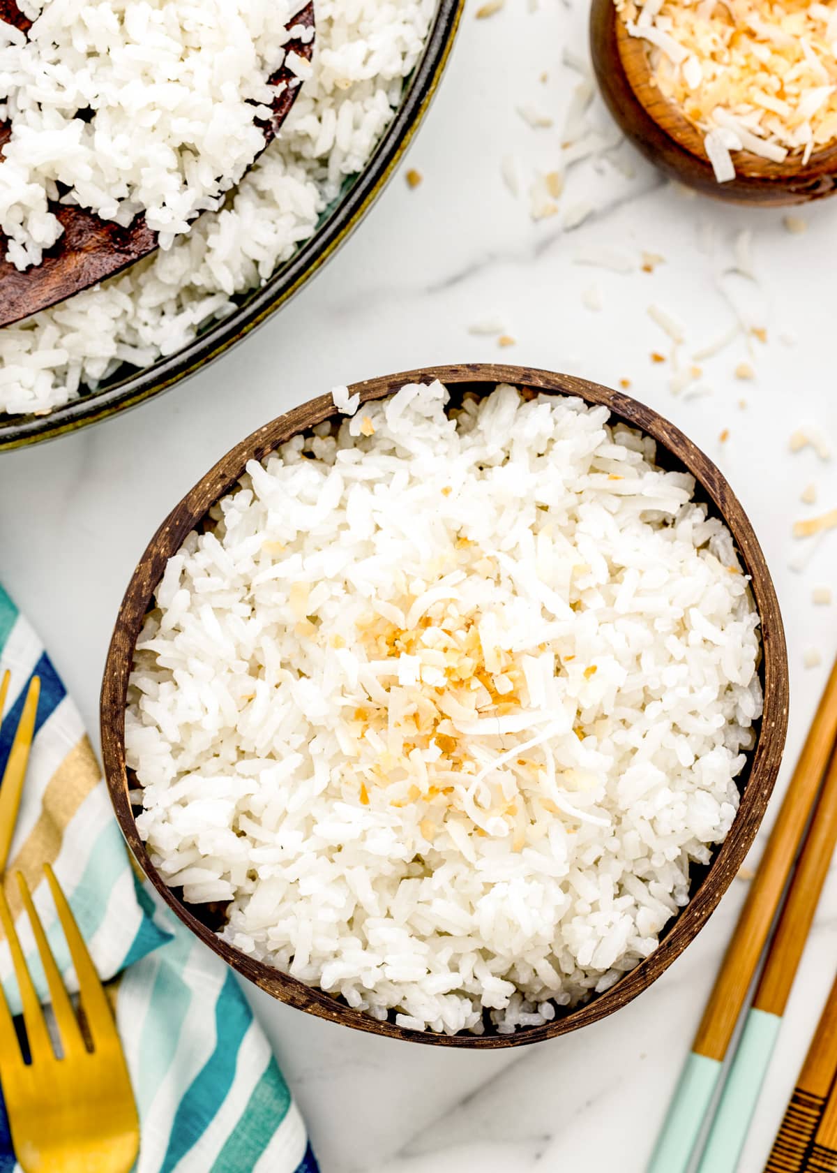 Close up of coconut rice served in a coconut bowl and topped with toasted coconut.