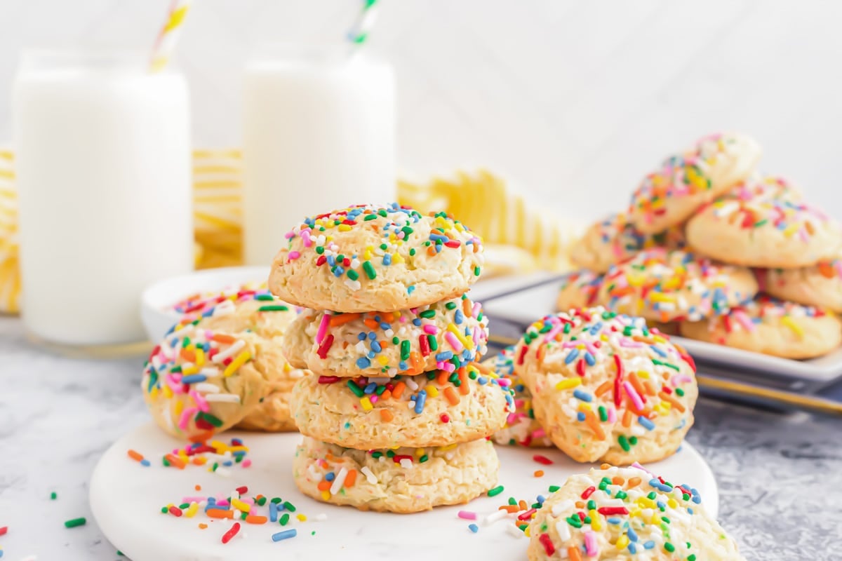 Stacked colorful funfetti cake mix cookies on a white plate.