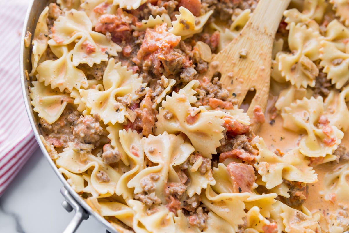 Italian Sausage and Pasta recipe in skillet with bowtie pasta mixed in.