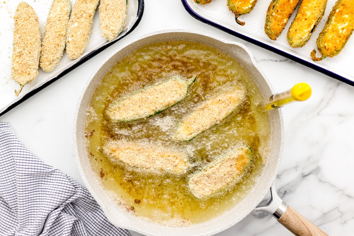 Frying jalapeno poppers in oil.