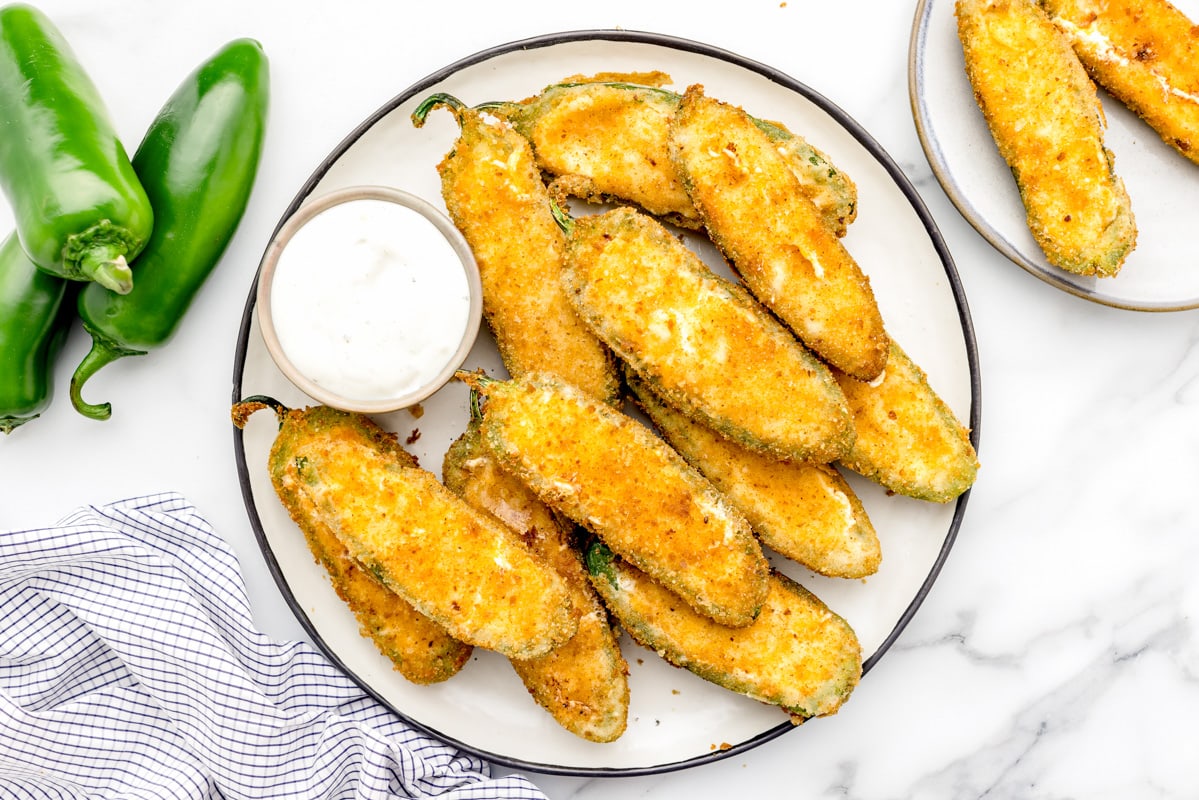 Jalapeno poppers served on a plate with ranch dressing.