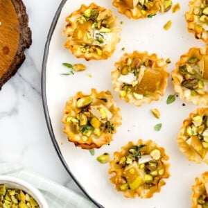 Brie and pear tarts served on a white plate.