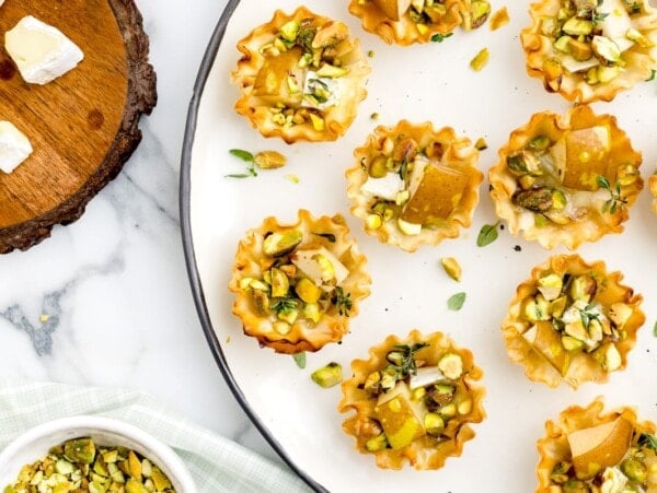 Brie and pear tarts served on a white plate.