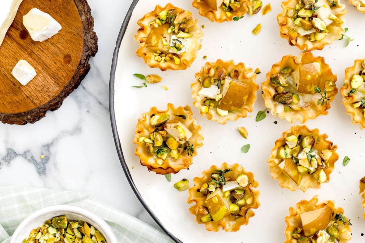 Brie and pear tarts served on a white plate.