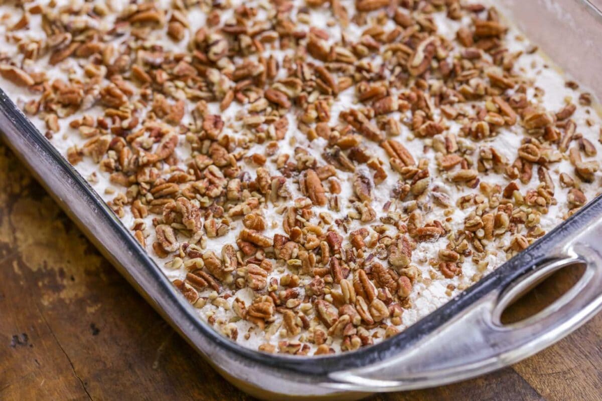 Adding nuts on top of pumpkin layer of pumpkin crunch cake.