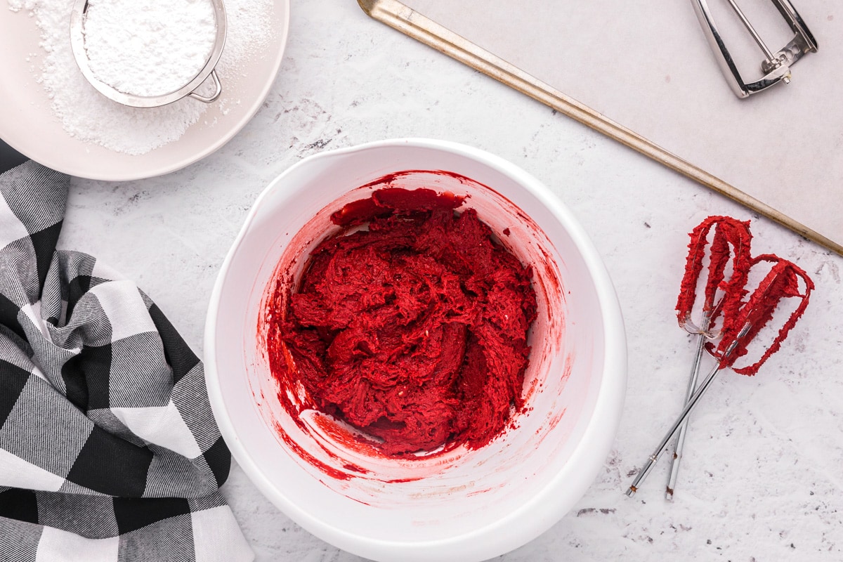 Red batter for red velvet cake mix cookies in a white bowl.