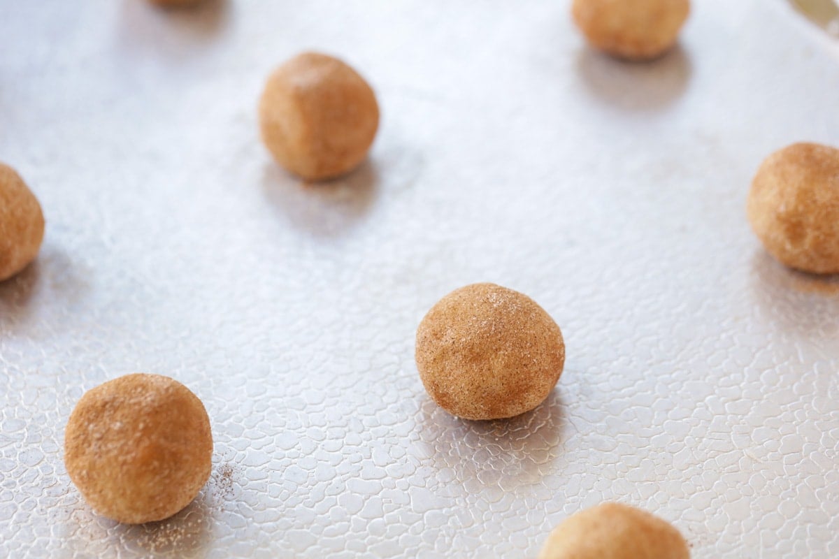 Snickerdoodle dough balls lined up on a cookie sheet.