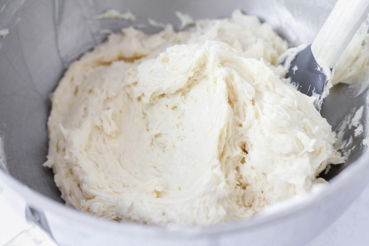 Mixing batter for sugar cookie bars in a metal bowl.