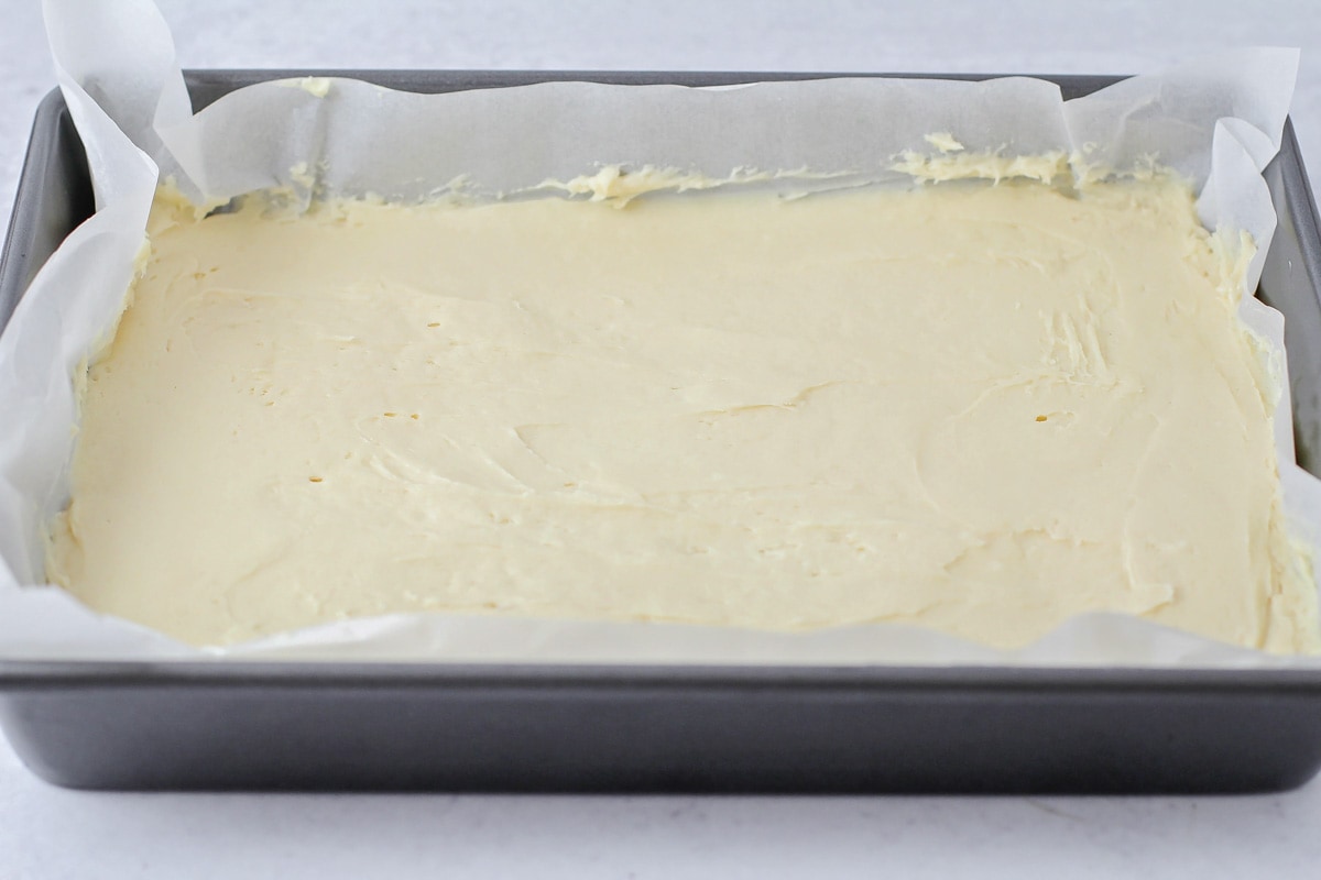 Spreading the sugar cookie bars batter in a parchment lined baking pan.