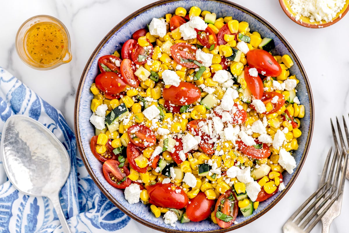 Corn salad topped with feta and Italian dressing in a bowl.