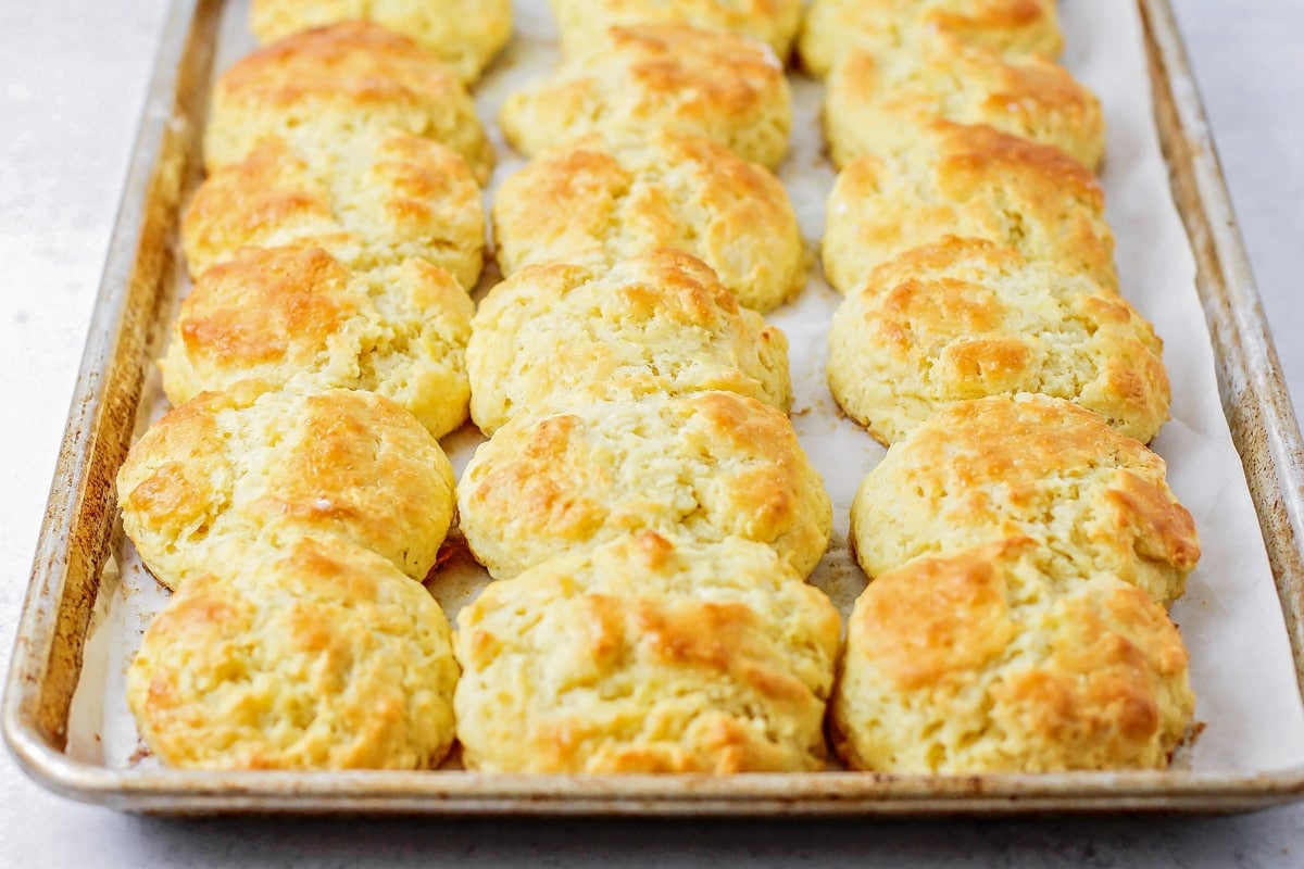 Golden brown biscuits on a lined baking sheet.