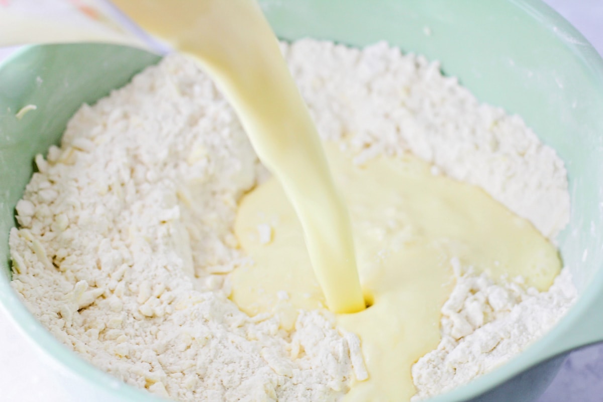 Adding buttermilk to a bowl of flour and butter.