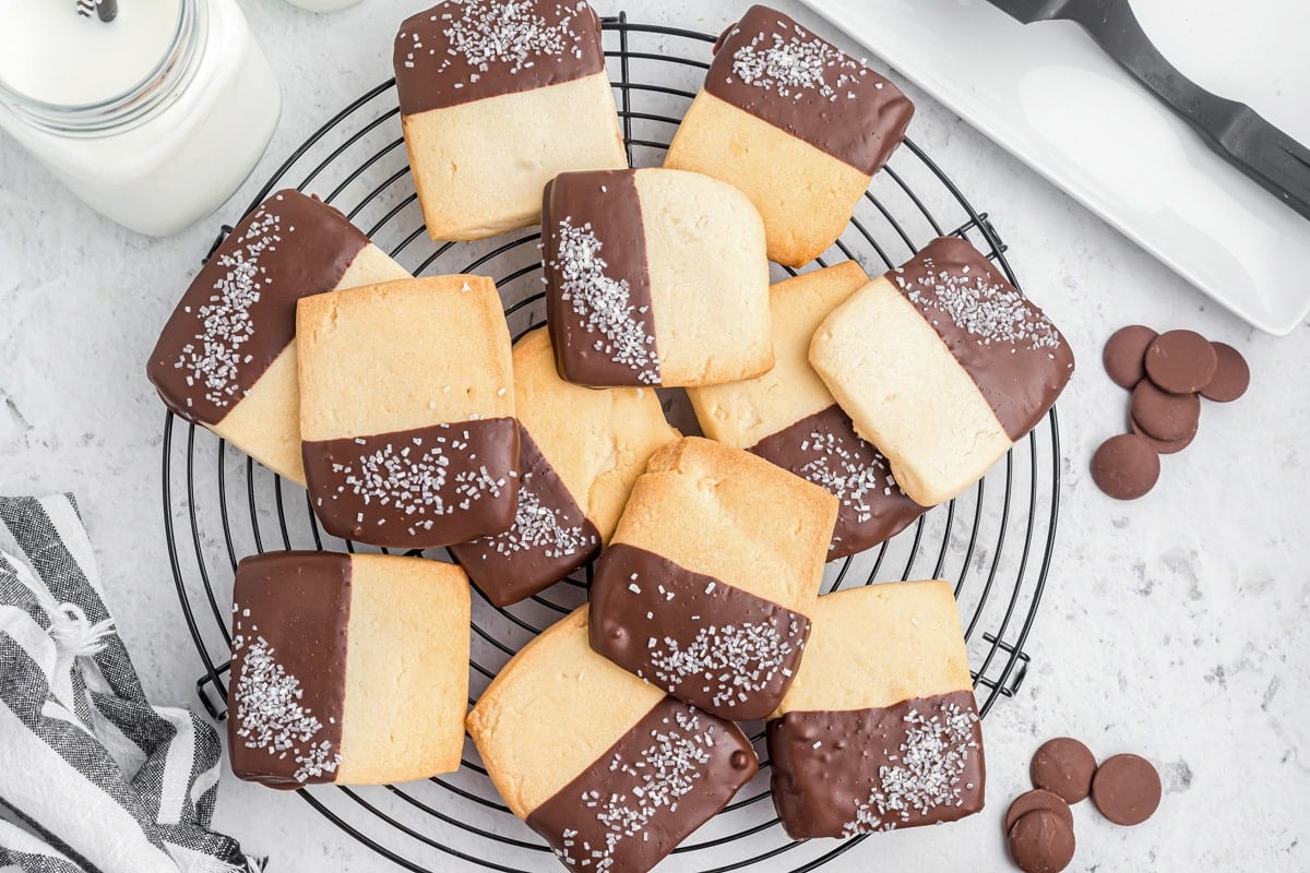 Several chocolate dipped cookies topped with coarse sugar on a cooling rack.