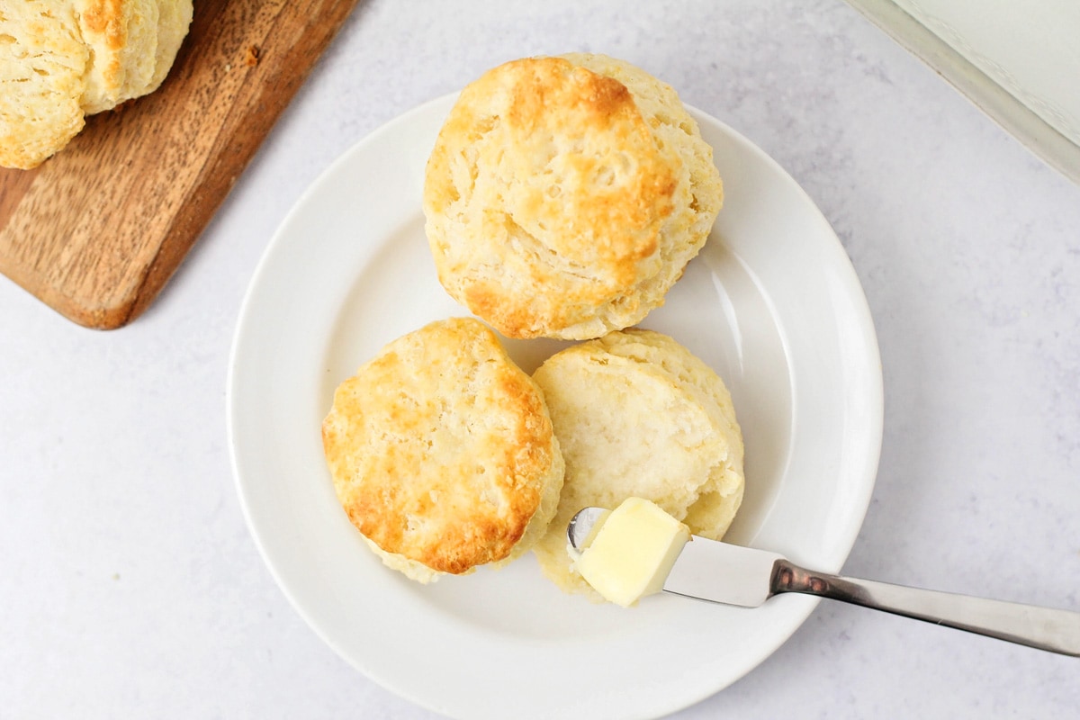 Two biscuits topped with butter on a white plate.