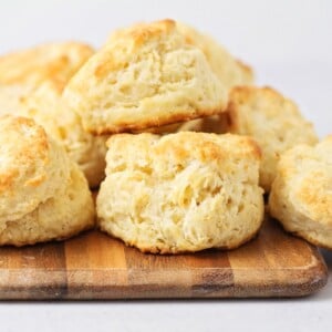 Several homemade biscuits stacked on a wooden tray.