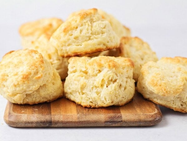 Several homemade biscuits stacked on a wooden tray.