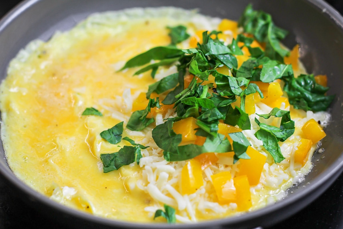 Adding cheese and filling to a cooking omelette.