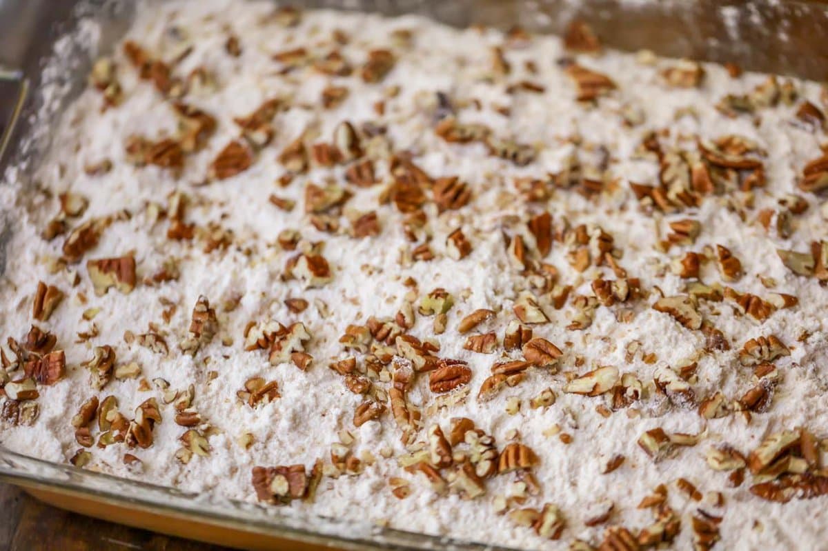 Layering cake mix and pecans on a pumpkin pie filling.