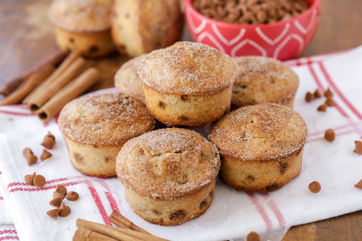 Several snickerdoodle muffins stacked on a tea towel.